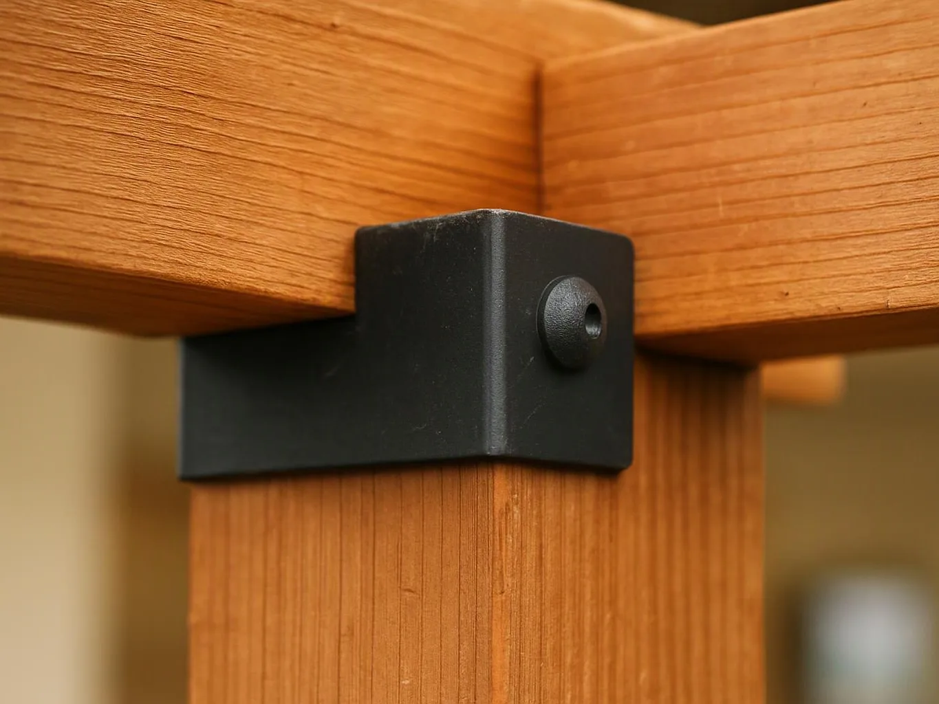 A black metal bracket fastens two wooden pieces together in a close-up indoor view