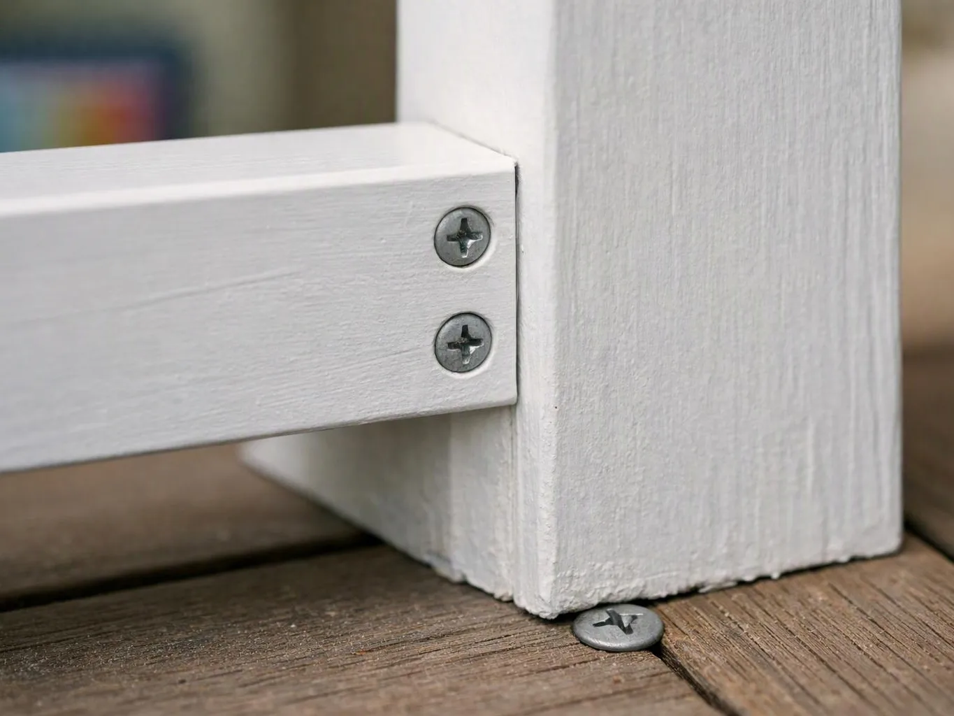 Close-up of a white wooden frame joined with screws on a weathered wood floor