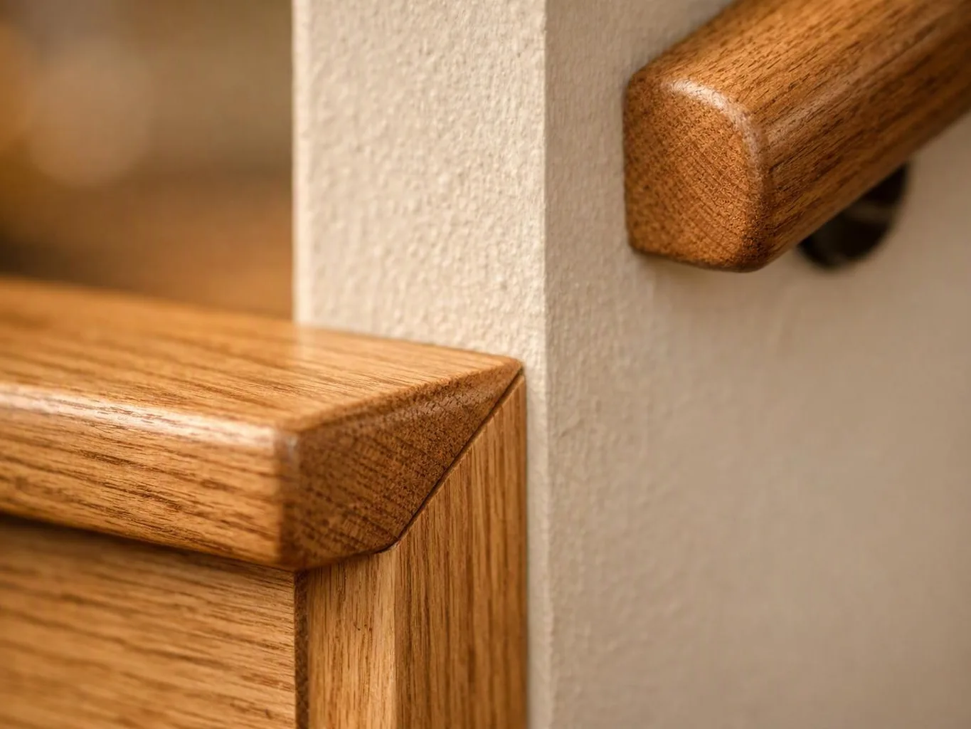 Close-up of wooden furniture corners meeting a textured white wall in warm light