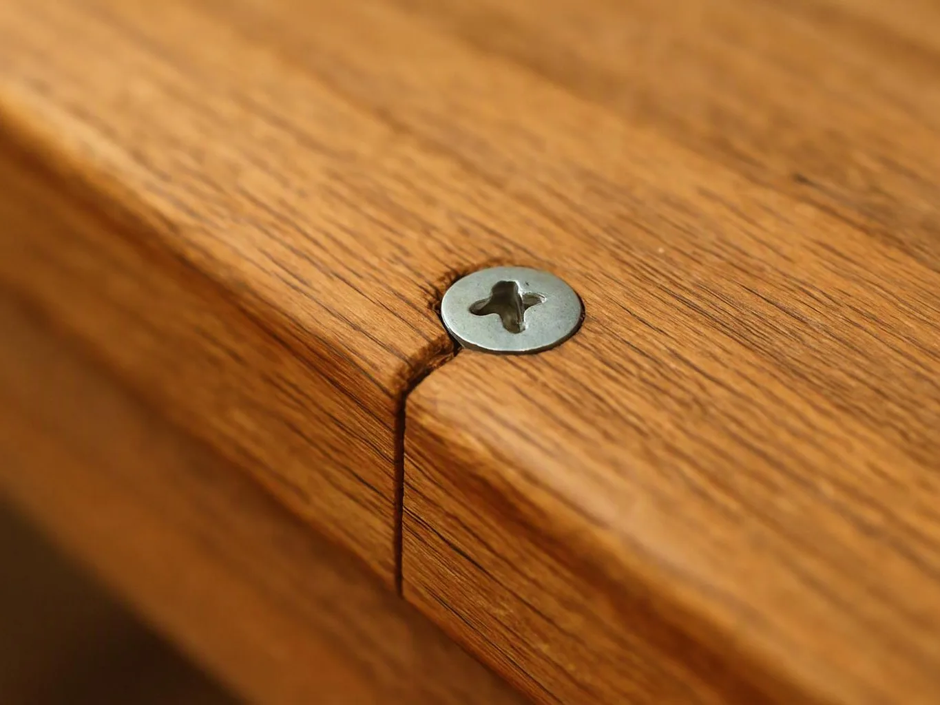 Close-up of a wooden surface with a metal screw fastener at a seam